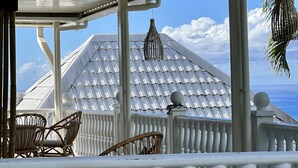 Un espace extérieur abrité, doté de balustrades blanches, de chaises en osier et offrant une vue sur l’océan.
