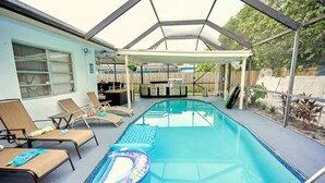 An indoor swimming pool with lounge chairs and a barbecue area. - The Royal Oasis heated pool (Lake Worth)