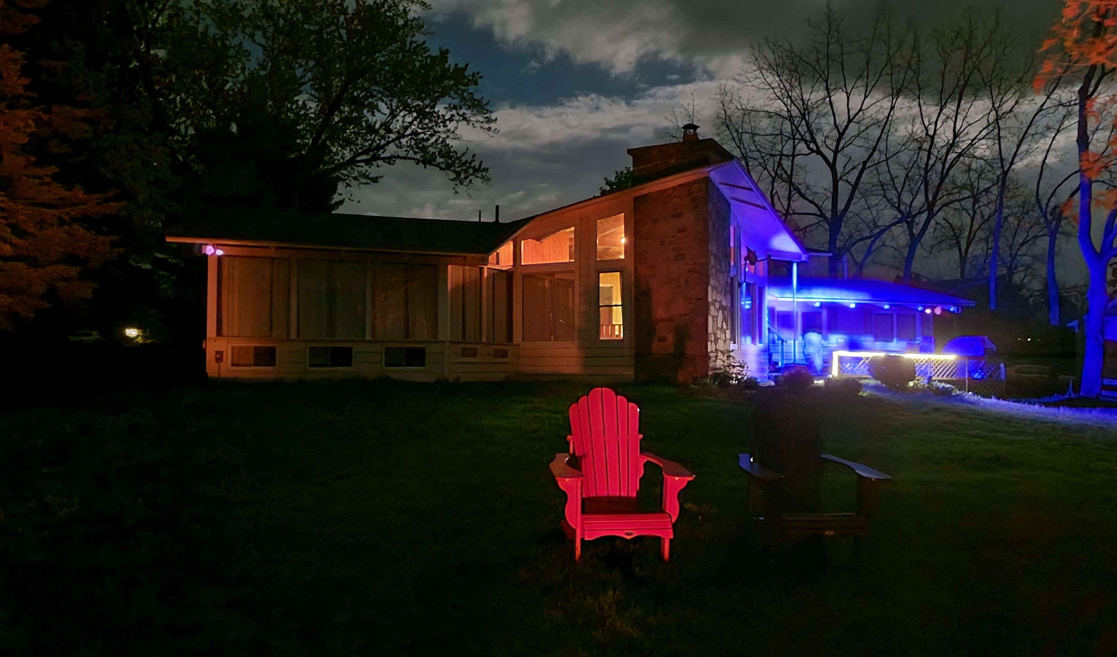 A house with a large front porch and a red chair in the yard.