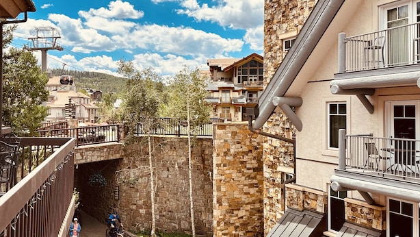Un immeuble à plusieurs étages doté de balcons, d’un mur en pierre et d’un pont piétonnier.