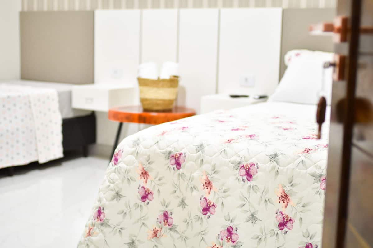Quarto de hotel bem organizado, com uma cama, uma mesinha e uma cadeira.
