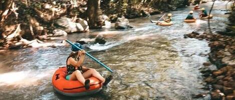 People in inflatable tubes on a river surrounded by trees.