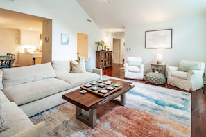 Un salon avec un canapé, des fauteuils, une table basse et un tapis.
