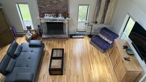 Una sala de estar con chimenea, piso de madera, un sofá, una mesa de centro y un televisor.