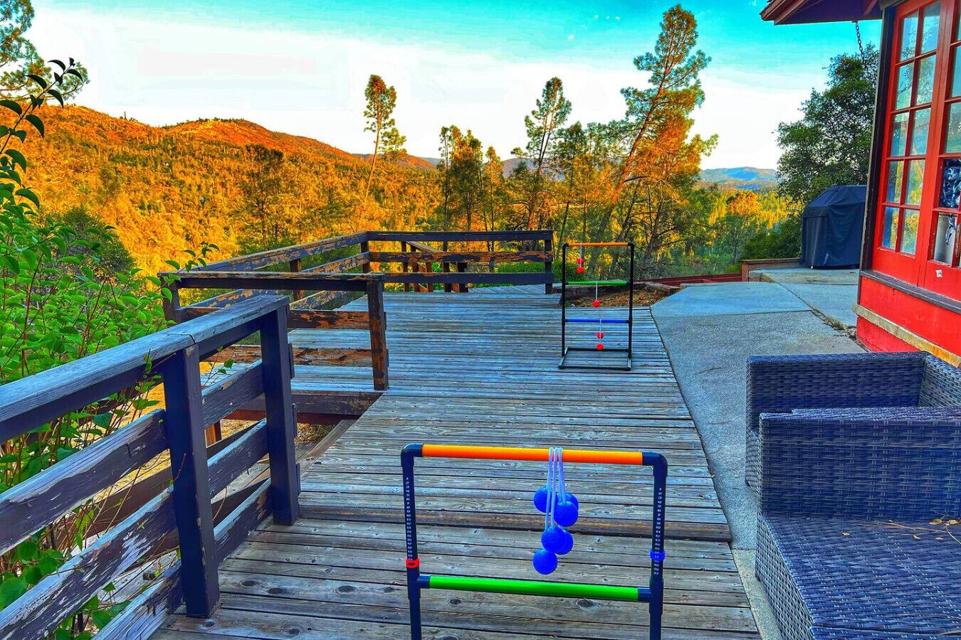 Une terrasse en bois équipée de matériel d’exercice, un bâtiment rouge et un paysage montagneux en arrière-plan.