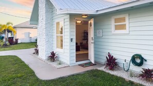 A house with a stone exterior, a metal roof, and a front door. - Coastal Gem: Pool, Hot Tub, King Bed, & More (Port St. Lucie)