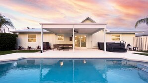 A house with a swimming pool, a covered patio, and a view of the sunset. - Coastal Gem: Pool, Hot Tub, King Bed, & More (Port St. Lucie)
