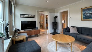 A modern living room with a flat-screen TV, a sofa, a coffee table, and a fireplace. - Beautiful holiday home in the center of Måløy (Vestland)