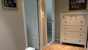 A hallway with a wooden floor, a white door, and a white dresser with multiple drawers. - Beautiful holiday home in the center of Måløy (Vestland)