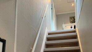 A staircase with wooden steps and white handrails, leading to a room with a white ceiling and recessed lighting. - Beautiful holiday home in the center of Måløy (Vestland)