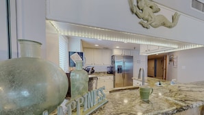 A modern kitchen with marble countertops, stainless steel appliances, and a decorative mermaid sculpture. - Corner Beachfront. Large Balcony. Pool. Hot Tub. Exceptional Location. (Madeira Beach)
