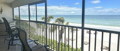 A balcony with a view of the beach and ocean.