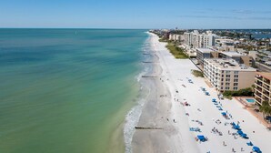 A beach with a row of buildings along the shore, featuring multiple floors and balconies. - Corner Beachfront. Large Balcony. Pool. Hot Tub. Exceptional Location. (Madeira Beach)