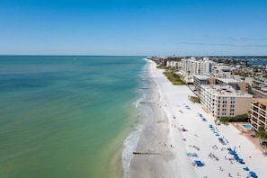 A beach with a row of buildings along the shore, featuring multiple floors and balconies. - Corner Beachfront. Large Balcony. Pool. Hot Tub. Exceptional Location. (Madeira Beach)