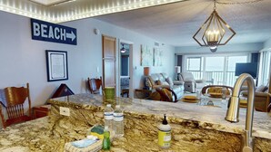 A kitchen with a marble countertop, a sink, and various kitchen items. There is a sign on the wall that says "BEACH" with an arrow pointing to the right. - Corner Beachfront. Large Balcony. Pool. Hot Tub. Exceptional Location. (Madeira Beach)