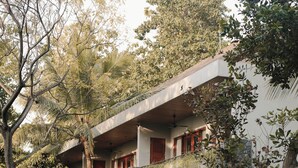 A modern building with a flat roof, multiple balconies, and lush greenery surrounding it. - Sanglung Villas (Kubutambahan)