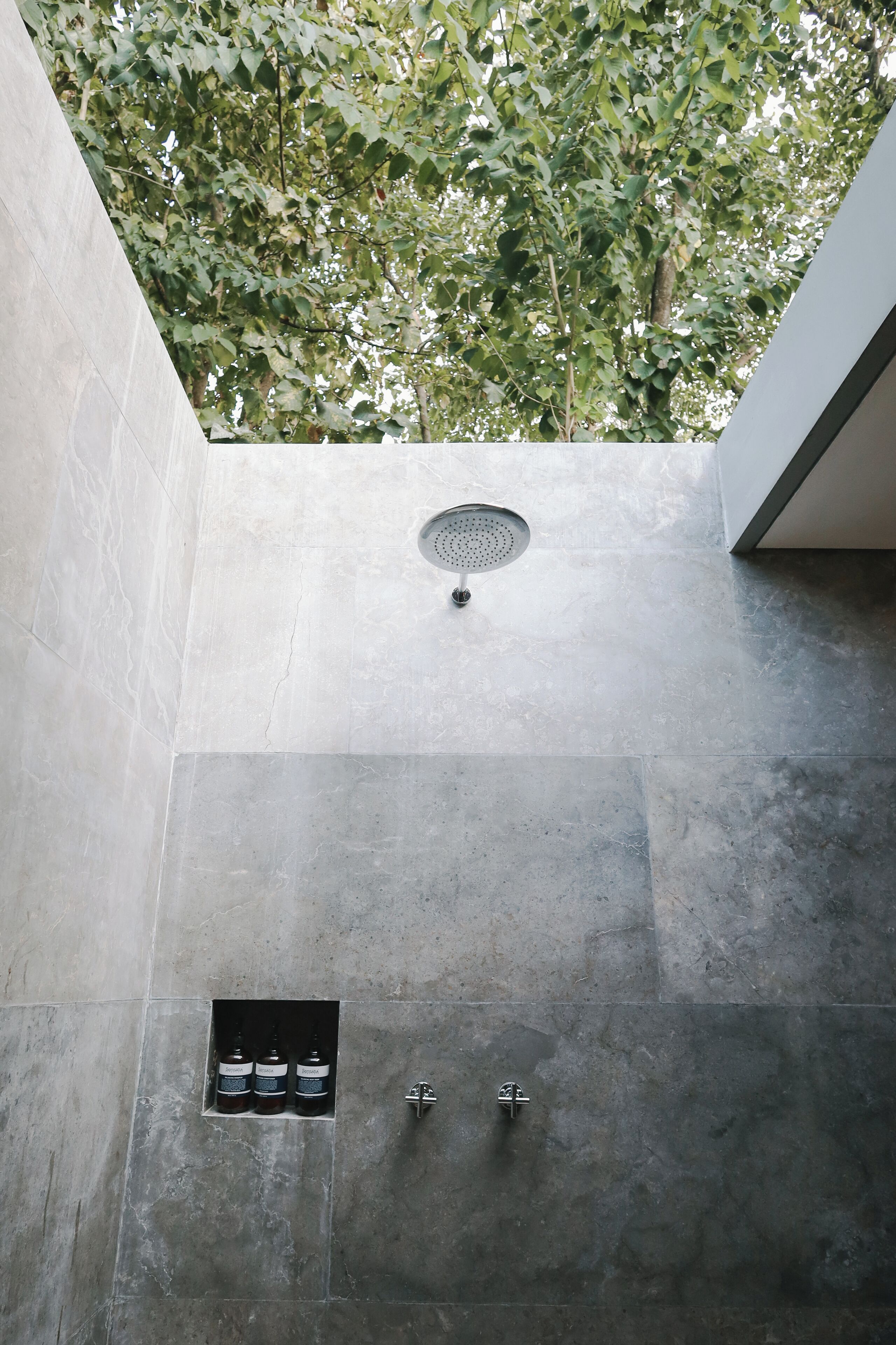 Un baño moderno con ducha integrada, una ventana pequeña y un lavabo instalado en la pared.