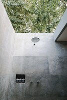 A modern bathroom with a built-in shower, a small window, and a wall-mounted sink.