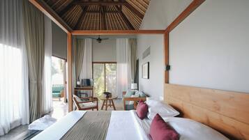 A hotel room with a large bed, a wooden headboard, a desk with a chair, a television, and a balcony with curtains.