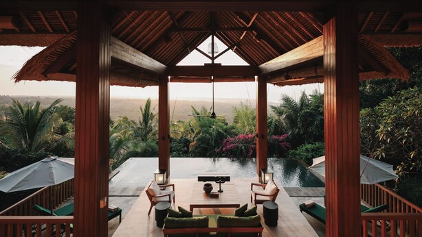 A covered outdoor seating area with a view of a pool and lush greenery. - Sanglung Villas (Kubutambahan)