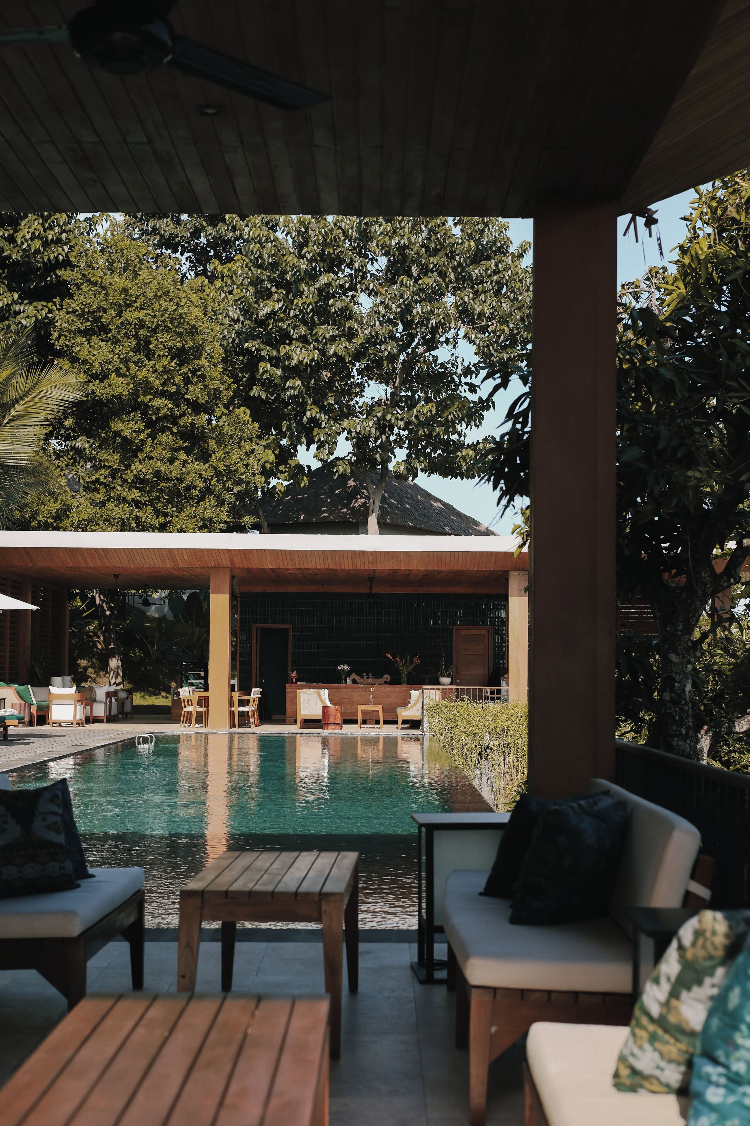 A pool area with lounge chairs and a bar, surrounded by trees.