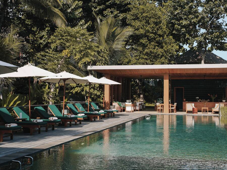 Una piscina al aire libre, sombrillas, tumbonas