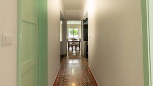 A hallway with a dining area at the end, featuring a table and chairs.