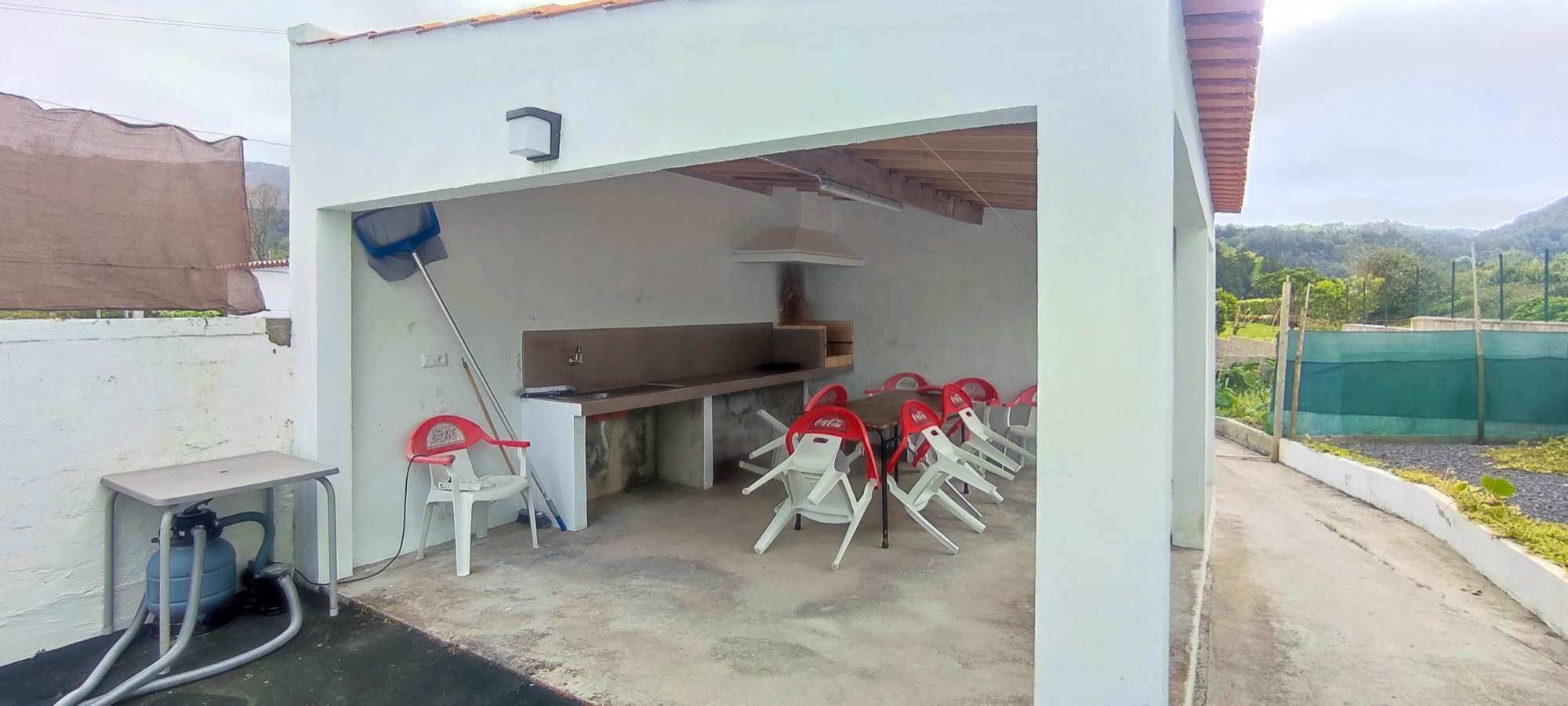 A small outdoor kitchen area with a table and chairs, a gas cylinder, and a water tap.