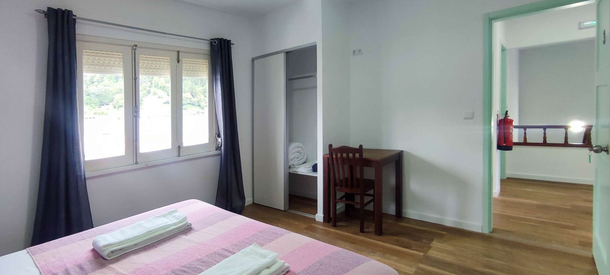 Une chambre à coucher comprenant un lit, une chaise, une armoire et une porte donnant sur une autre pièce.