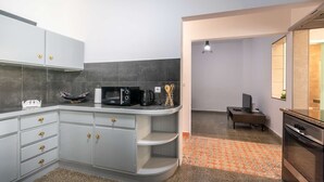 A modern kitchen with grey cabinets, a microwave, and a coffee maker. There is a small dining area with a table and chairs.