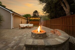 Patio con un hogar de piedra, mobiliario exterior y una valla de madera.