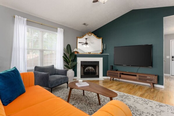 Una sala de estar con chimenea, un televisor de pantalla plana grande y un sofá moderno.