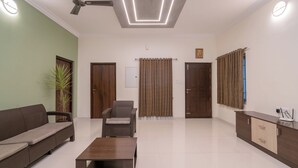 Un ampio soggiorno con divano, poltrona e tavolino, una ventola a soffitto e un moderno lampadario.