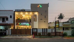 Un edificio moderno con un cartello che indica l'hotel "The Surya Max", caratterizzato da un ingresso imponente e una facciata ben illuminata.