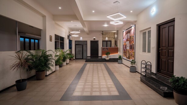 Una hall d'albergo con pavimento piastrellato, piante in vaso, una reception e un grande poster appeso al muro.