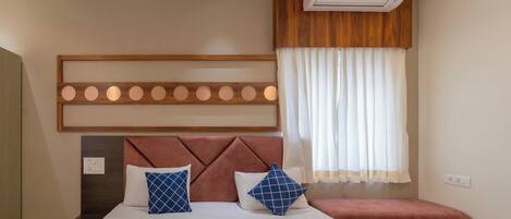 A bedroom with a bed, a headboard, a bedside table, a bench, an air conditioning unit, and a window with curtains.