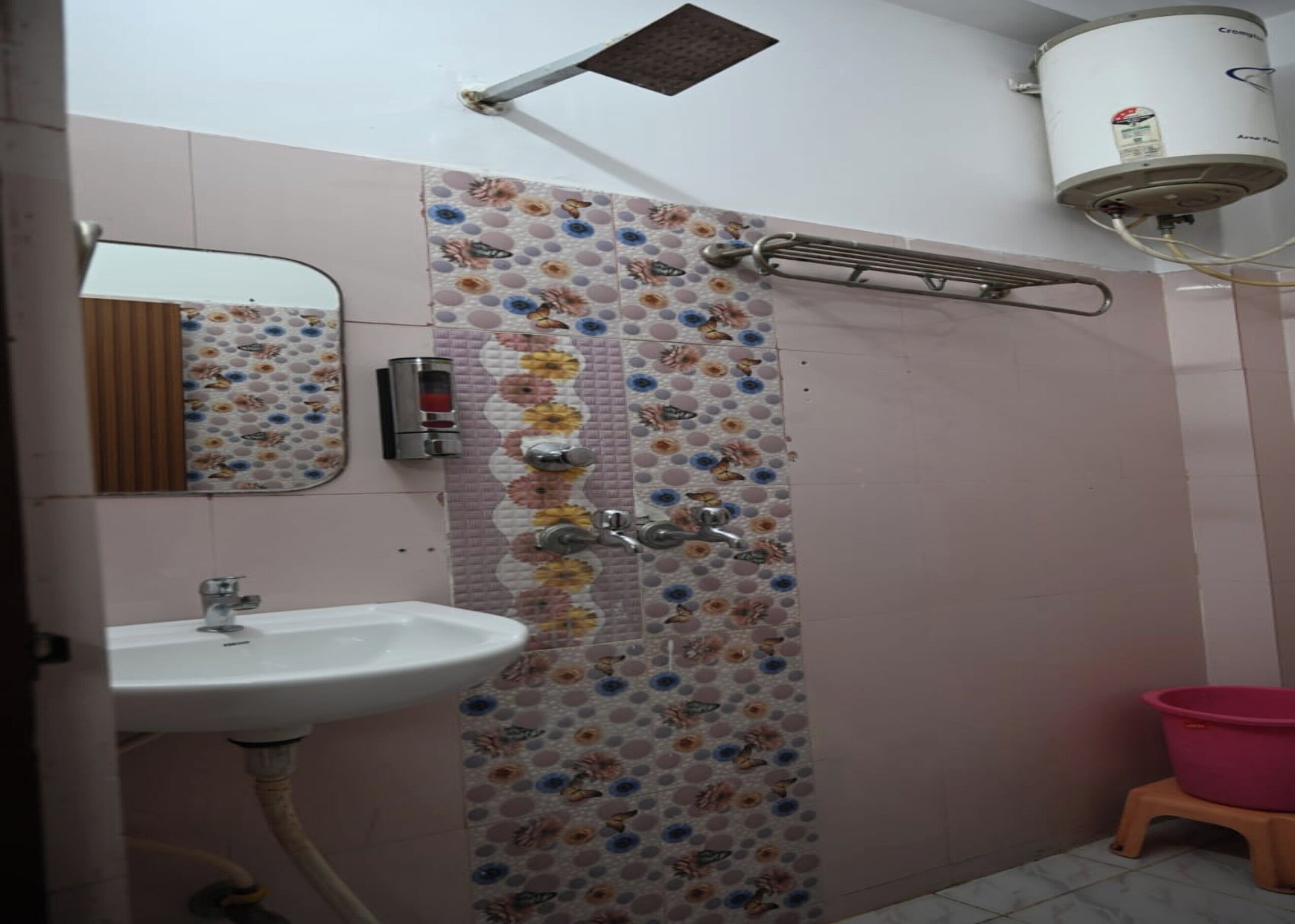 A bathroom with a shower, a sink, a mirror, a heater, and a small stool.