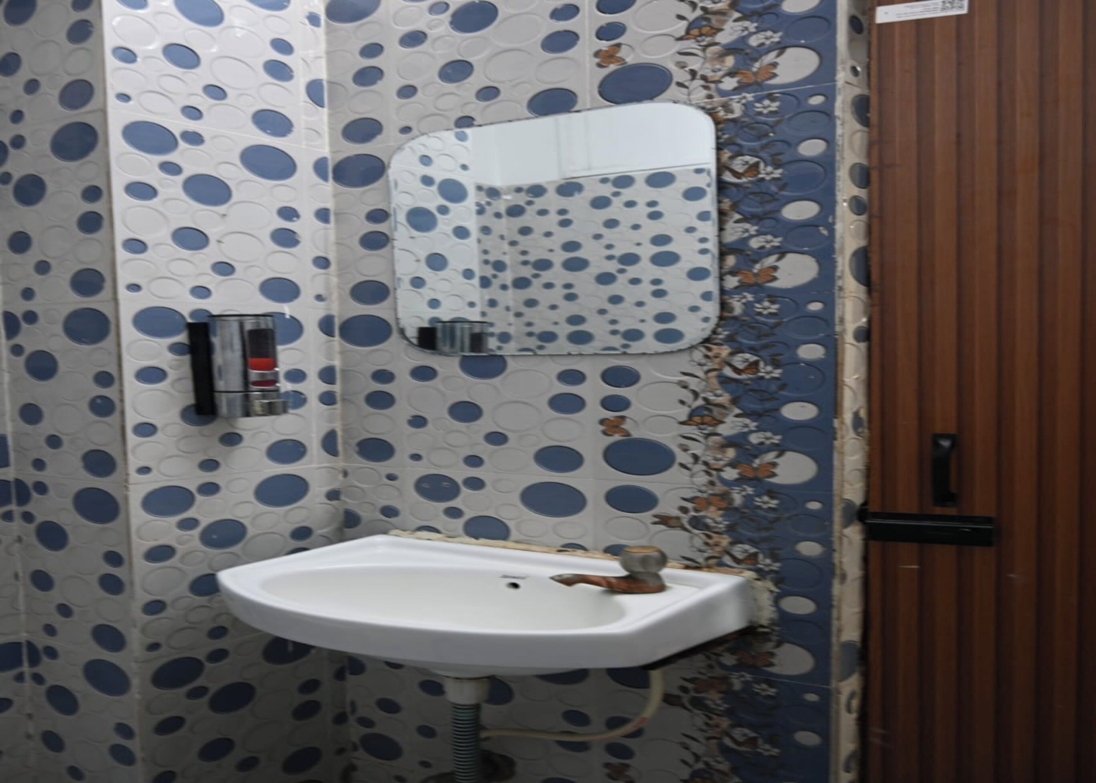 A bathroom with a white sink, a mirror, and patterned walls.