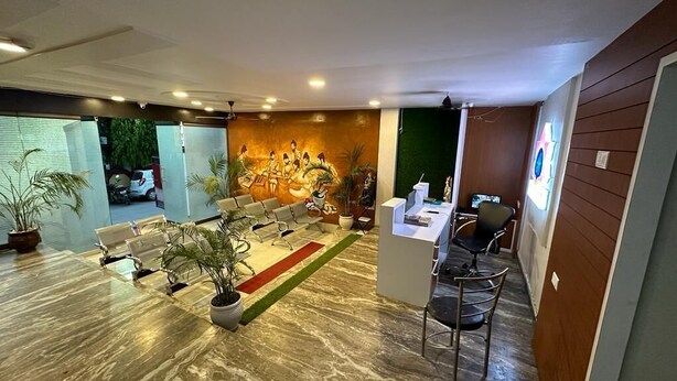 A modern reception area with a seating area, a reception desk, and a mural on the wall. - Hotel Aparajita (Varanasi)
