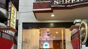 A hotel entrance with a red carpet, a glass door, and a sign above the door. - Hotel Aparajita (Varanasi)