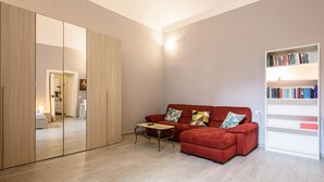Ein modernes Wohnzimmer mit einem roten Sofa, einem kleinen Tisch, einem Bücherregal und einem großen Spiegel.