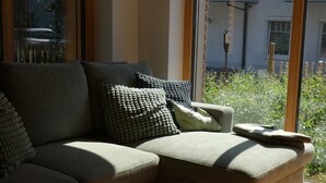 Un sofá modular con varios cojines en una habitación con ventanas grandes.