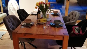 Una mesa de comedor dispuesta con platos, tazones, una botella y un jarrón de flores.
