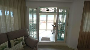 Un soggiorno con divano, una porta vetrata che dà sull'esterno e vista su un patio.