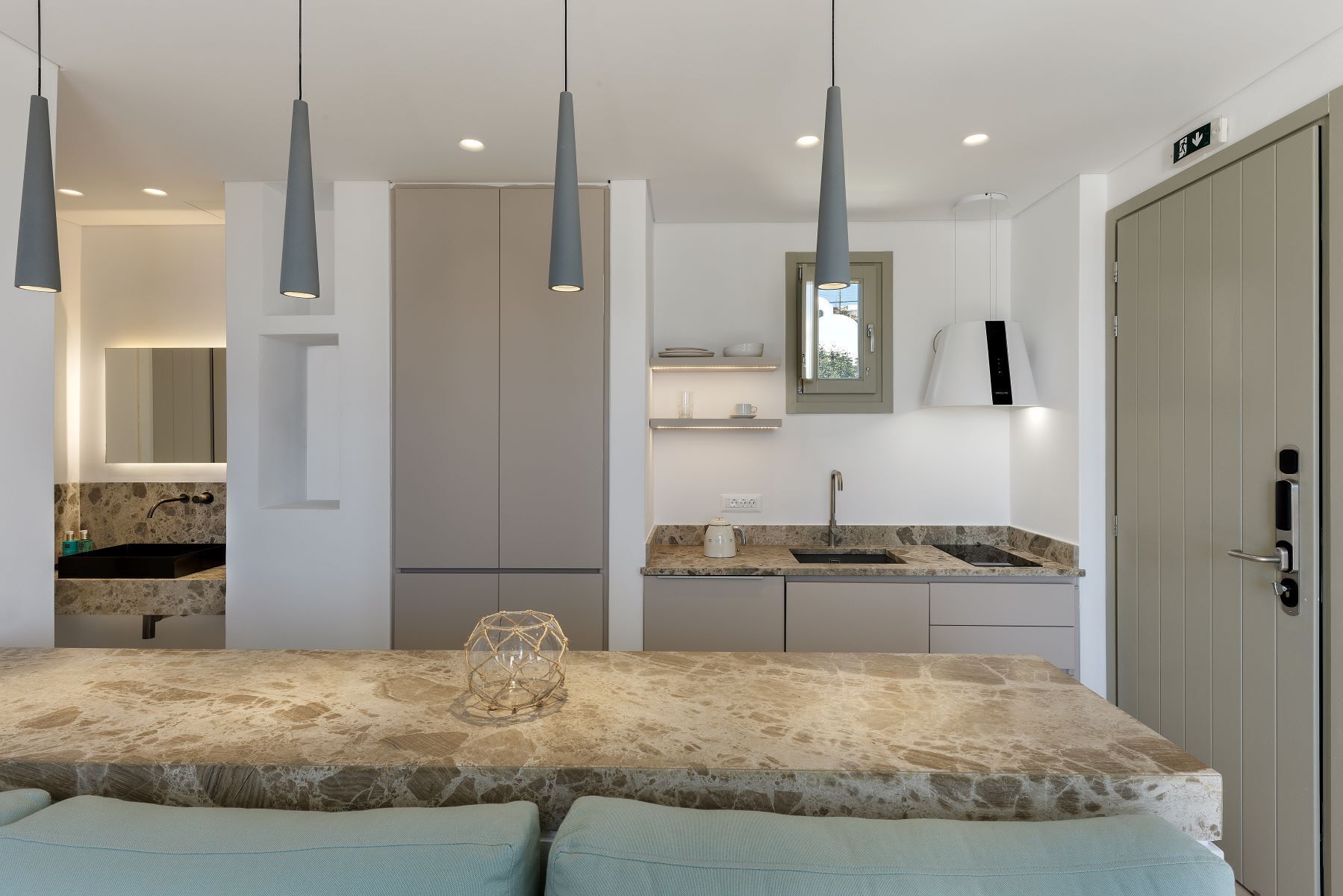 A modern kitchen with a stone countertop, pendant lights, and built-in cabinets.