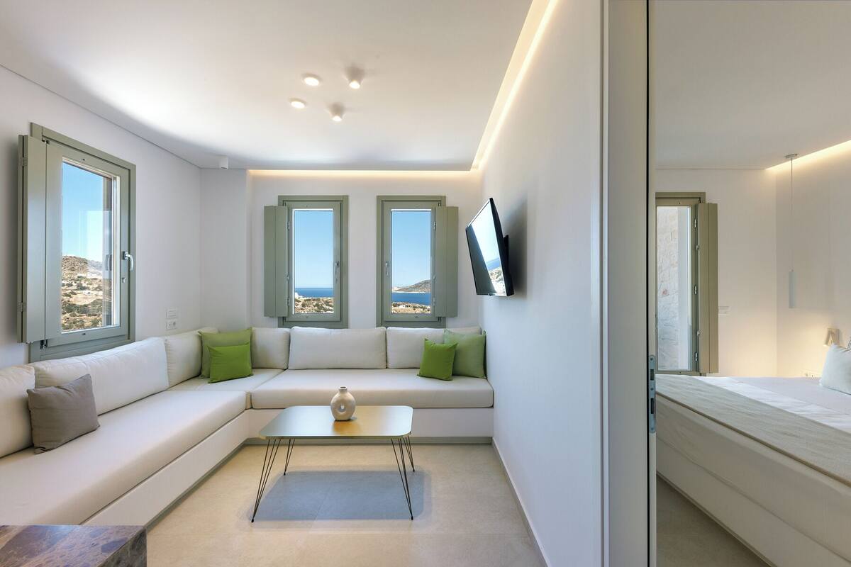 A modern, compact room with a sofa, a small table, and a TV mounted on the wall.