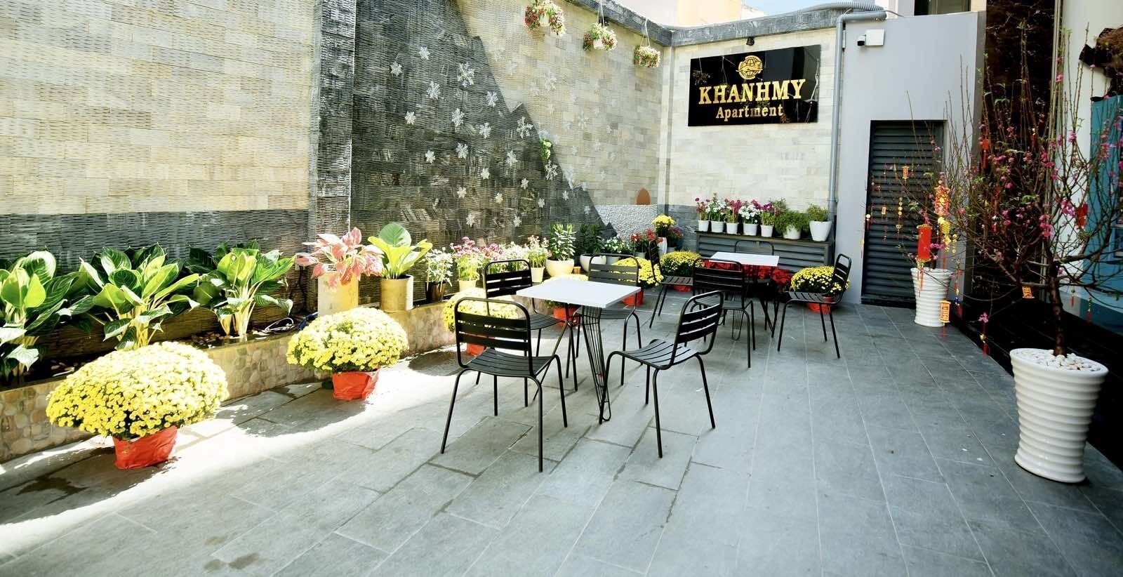 An outdoor patio area with a table and chairs, surrounded by potted plants and flowers.