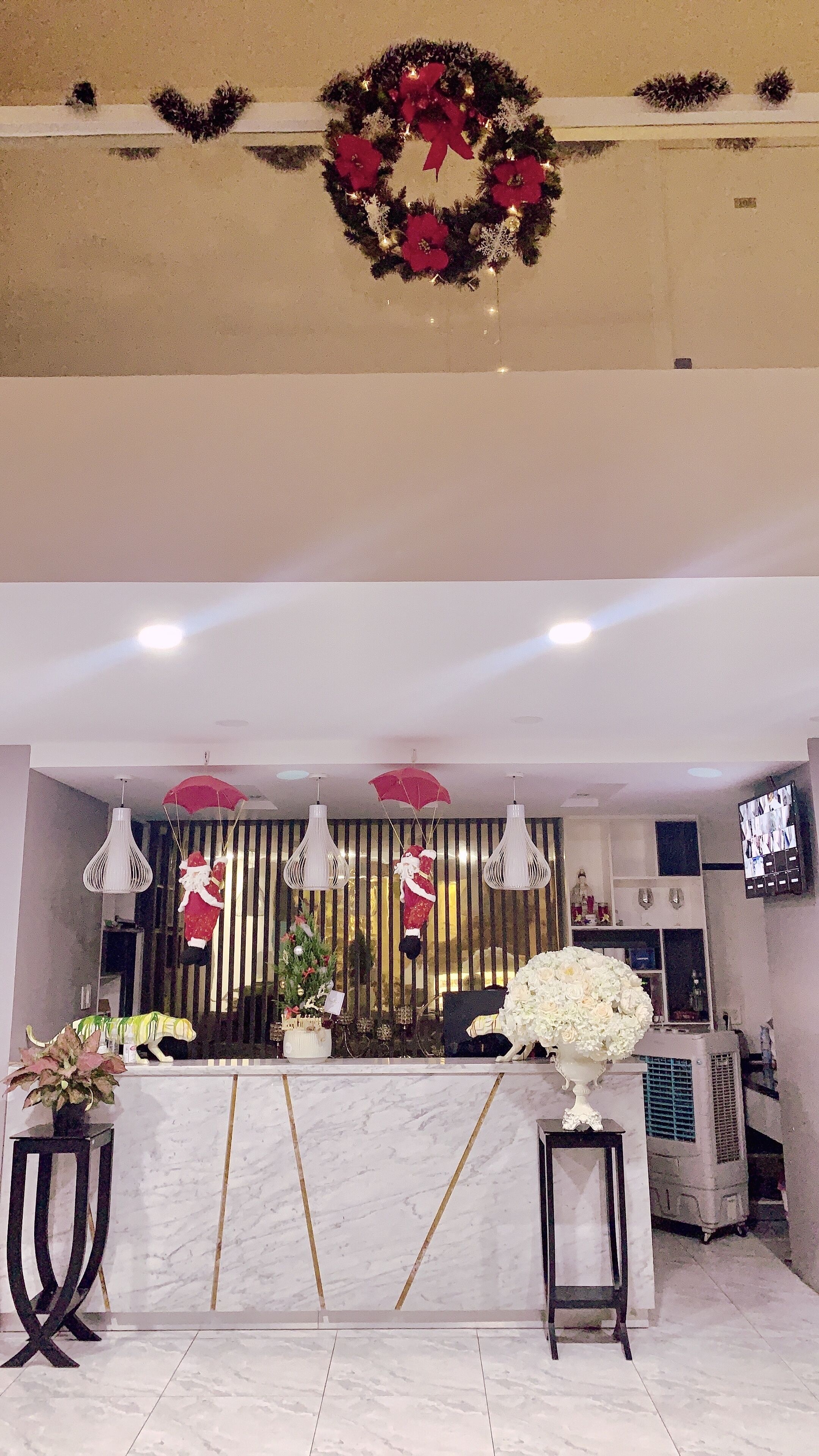 A hotel reception area with a marble counter, a Christmas wreath, and holiday decorations.