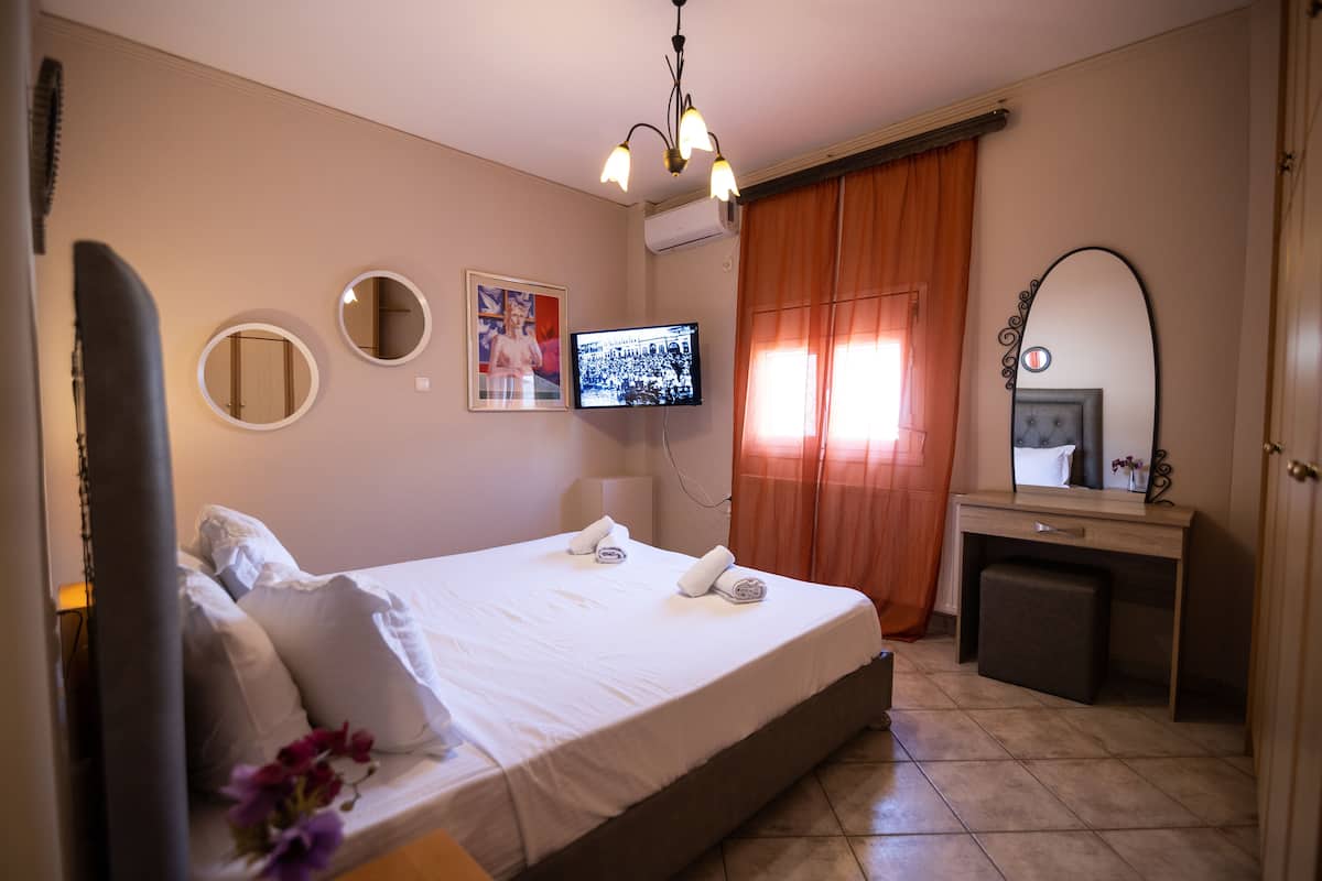 A hotel room with a bed, a desk, a television, and a mirror.