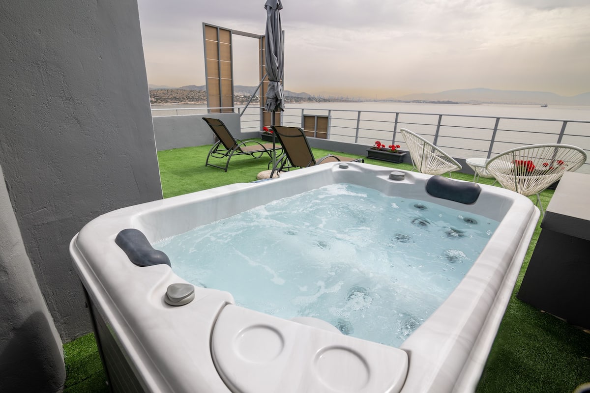 A hot tub on a balcony with a view of the sea and mountains.